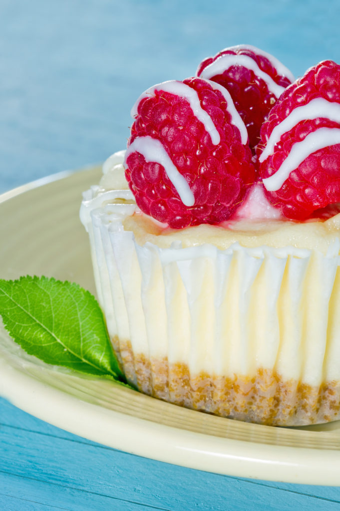 Closeup of cheesecake cupcake with raspberry, light blue background