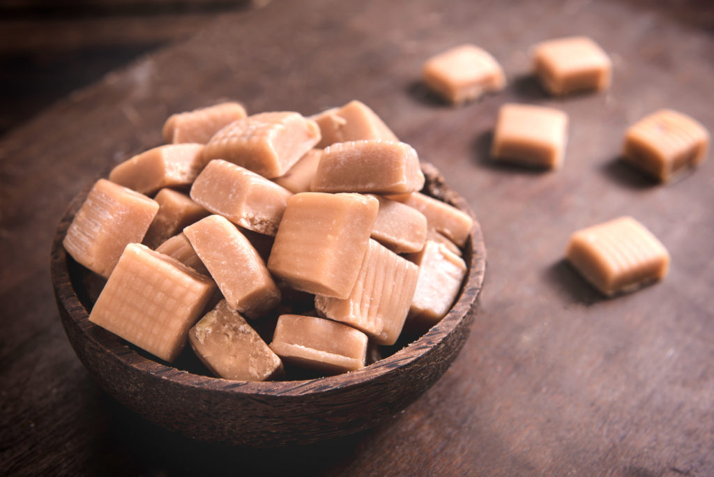 Milk and caramel handmade bonbons on wooden background,